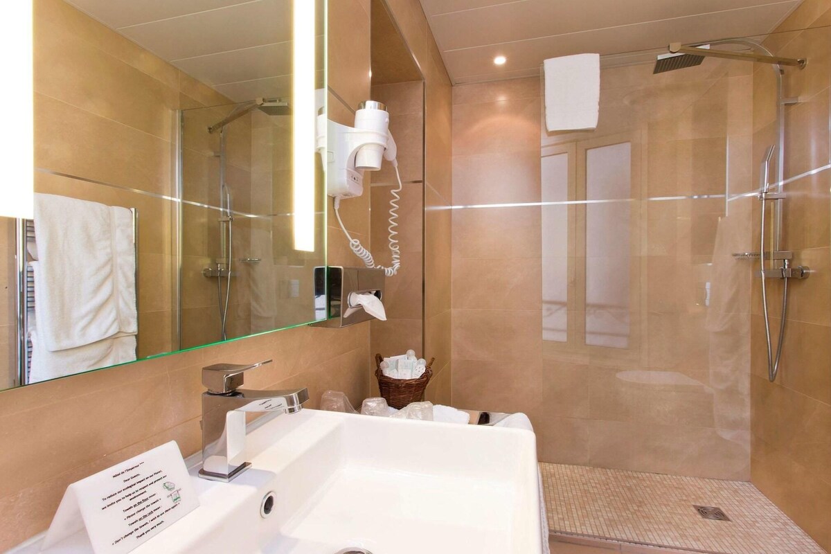 A modern bathroom with a glass-enclosed shower, a white sink, and a mirror.