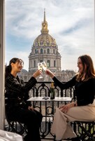 Two people toasting with champagne glasses on a balcony with a view of a large domed building.