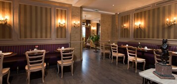 Un restaurante con sillas y mesas de madera, paneles en las paredes a rayas y luminarias fijadas a la pared.
