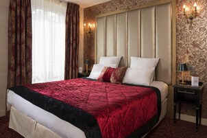 A hotel room with a large bed, a headboard, two bedside tables, and a window with curtains.