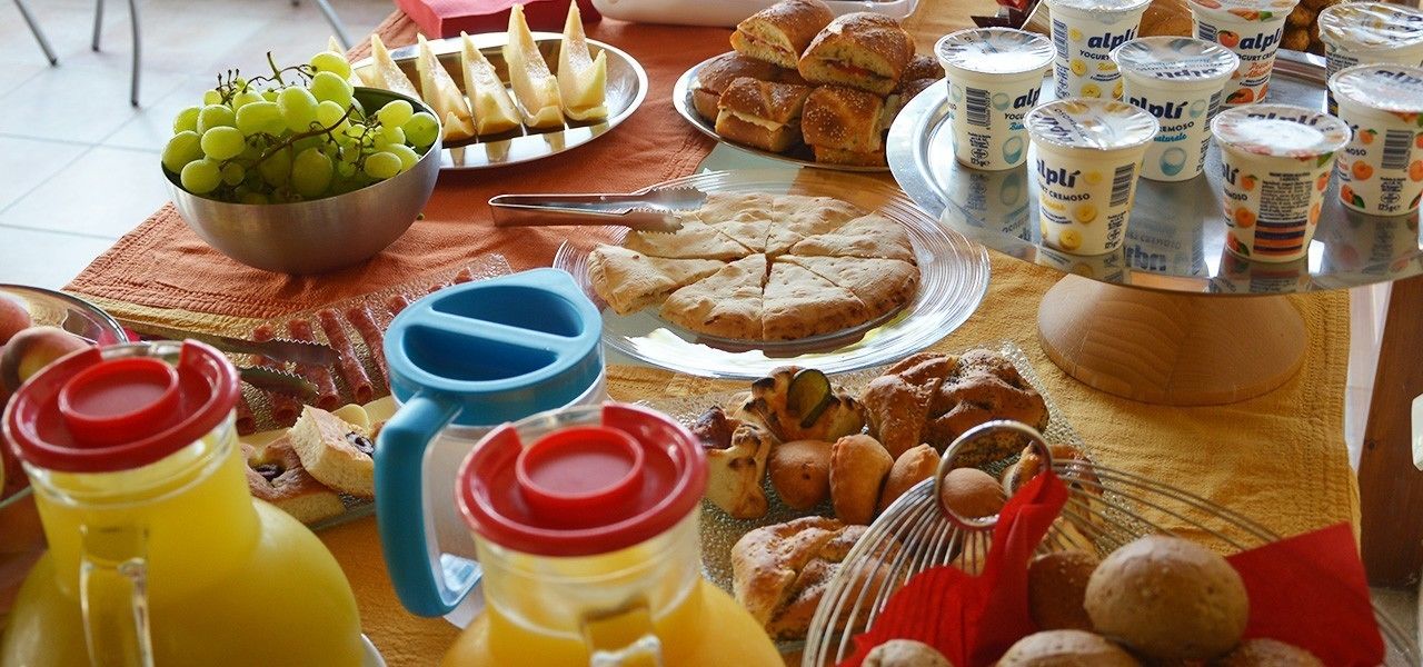 Ein reichhaltiges Buffet mit verschiedenen Speisen, darunter eine Schüssel Trauben, Brot, Gebäck und Joghurts.