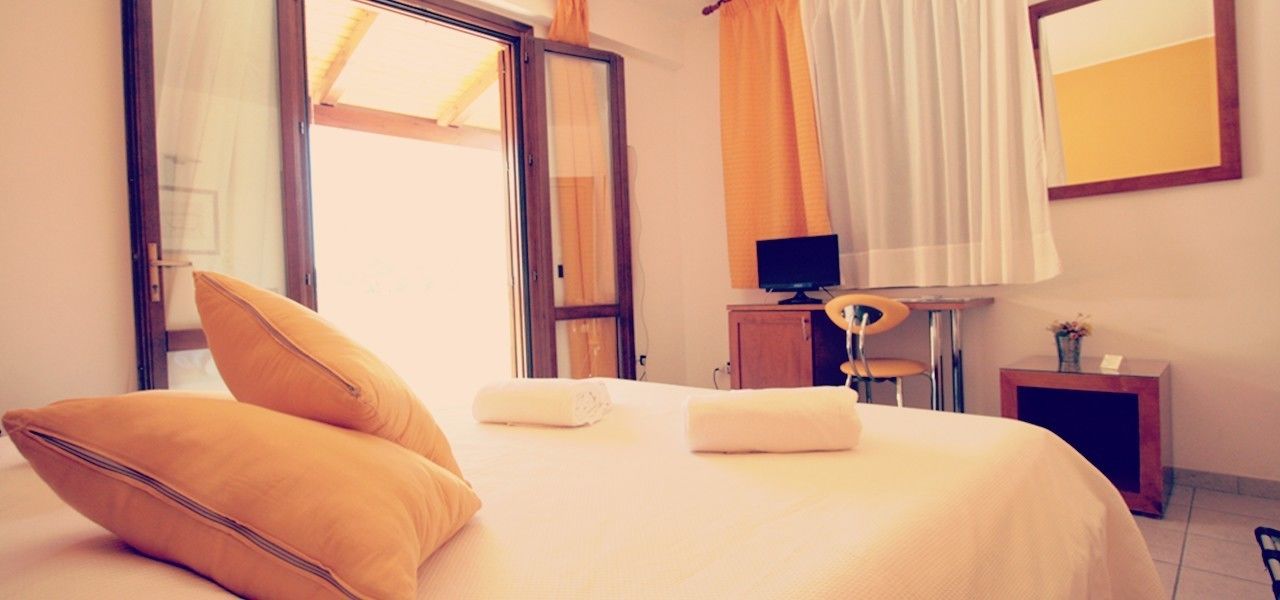 Une chambre d’hôtel avec un lit, une télévision, un bureau et une fenêtre avec des rideaux.