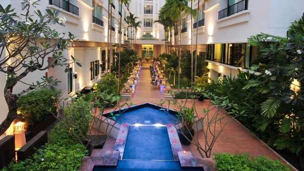 A hotel courtyard with a central pool, surrounded by lush greenery and palm trees. - Tara Angkor Hotel (Siem Reap)