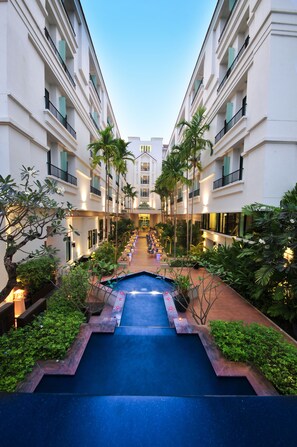 A hotel courtyard with a central pool, surrounded by lush greenery and palm trees. - Tara Angkor Hotel (Siem Reap)