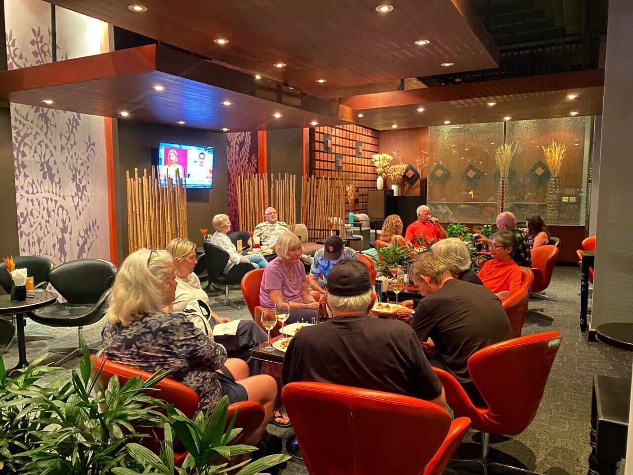 Un grupo de personas sentadas en una mesa en un ambiente interior moderno con detalles de madera y plantas.