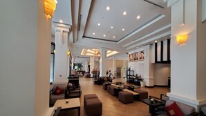 A spacious lobby with seating areas, a reception desk, and a view of the dining area. - Tara Angkor Hotel (Siem Reap)