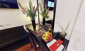 A hotel room with a piano, a dining table with fruit and a red napkin, and two potted plants. - Tara Angkor Hotel (Siem Reap)