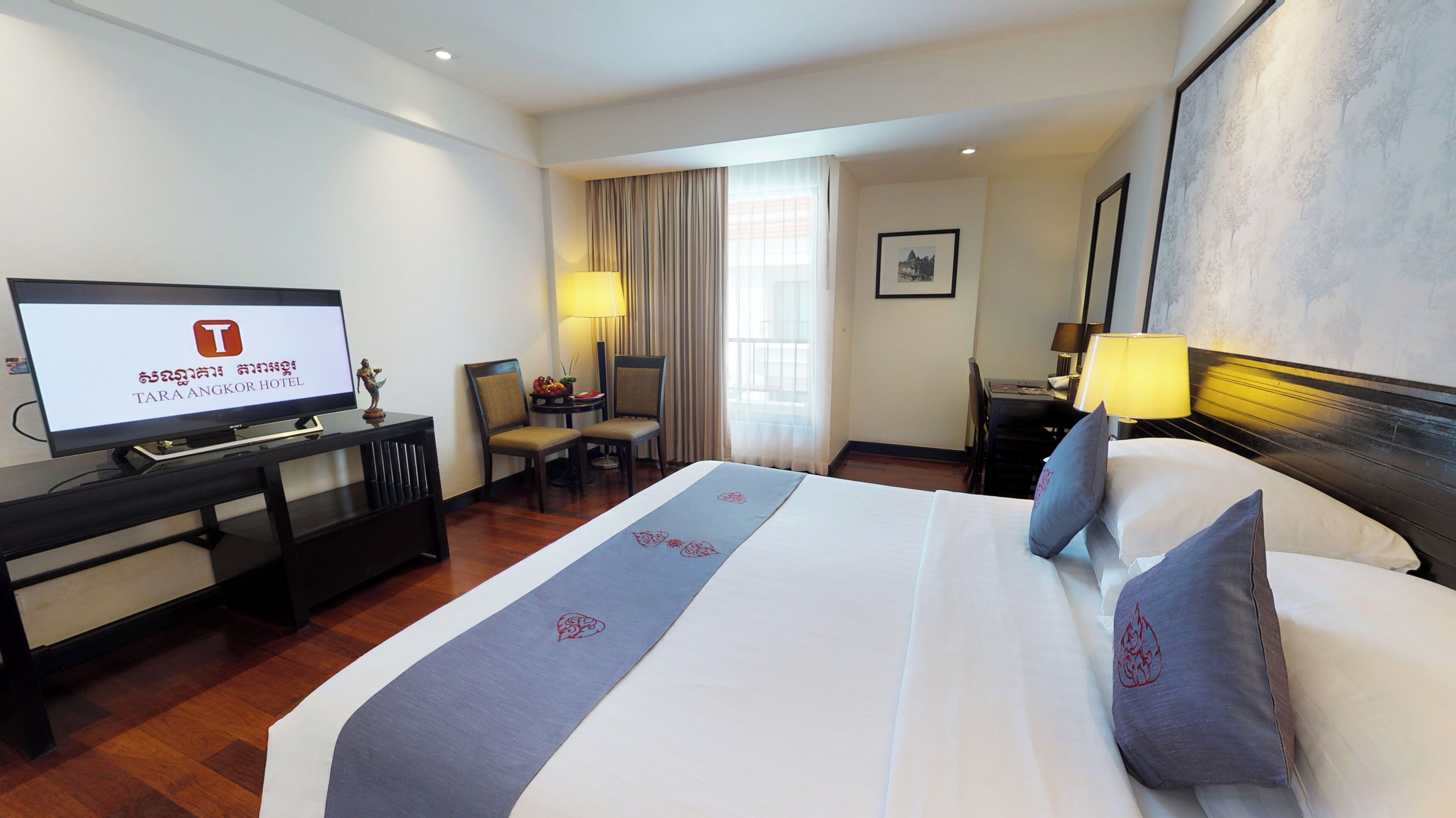 A hotel room with a bed, a desk, a chair, a television, and a window with curtains.