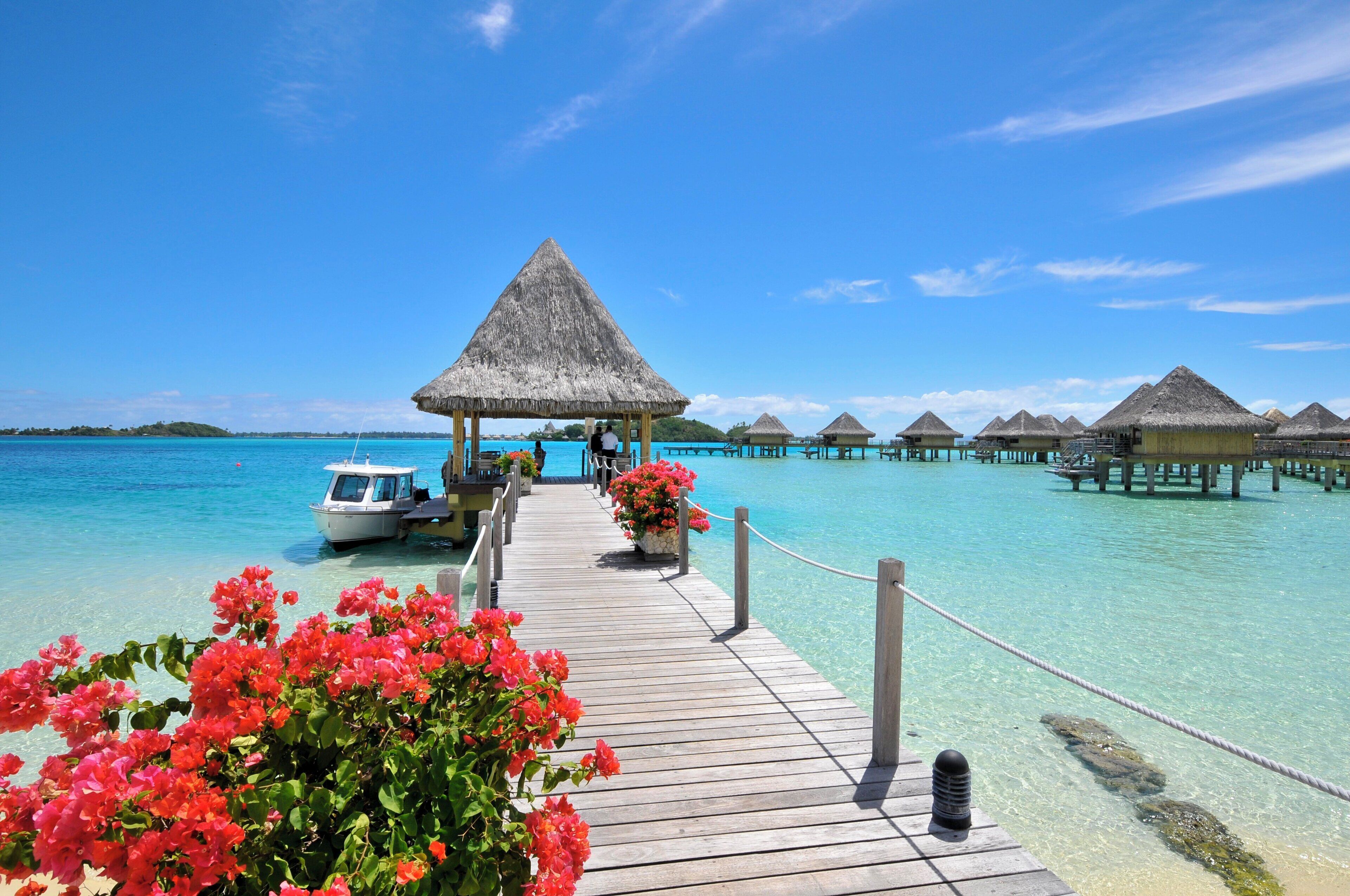A wooden pier leading to overwater bungalows with clear turquoise water.