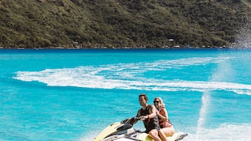 A jet ski on turquoise water with a mountainous landscape in the background.