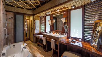 Une salle de bain spacieuse avec une grande baignoire, deux lavabos et un espace coiffeuse.