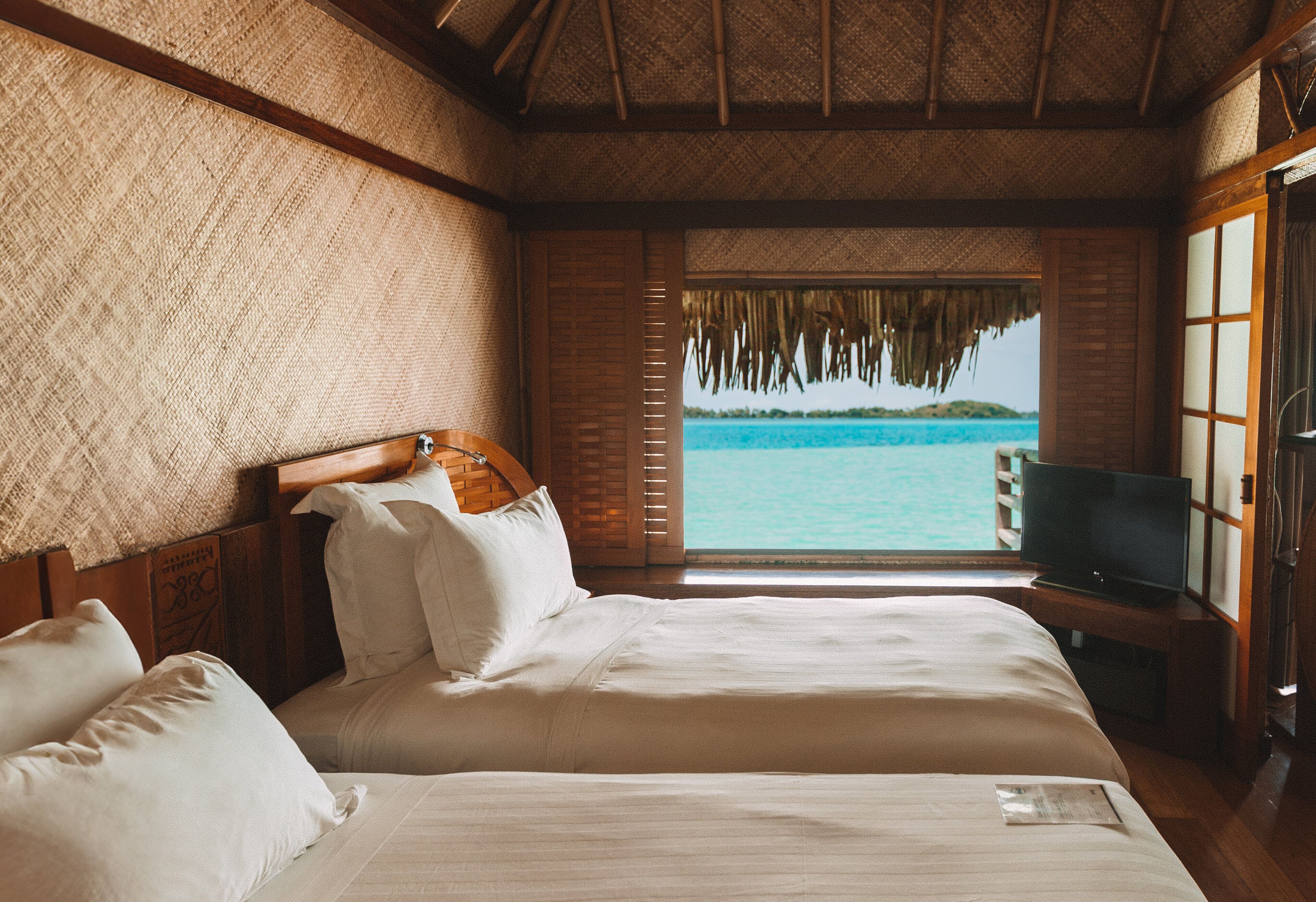 A bedroom with a large bed, a television, and a view of the ocean.