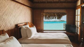 A bedroom with a large bed, a television, and a view of the ocean.