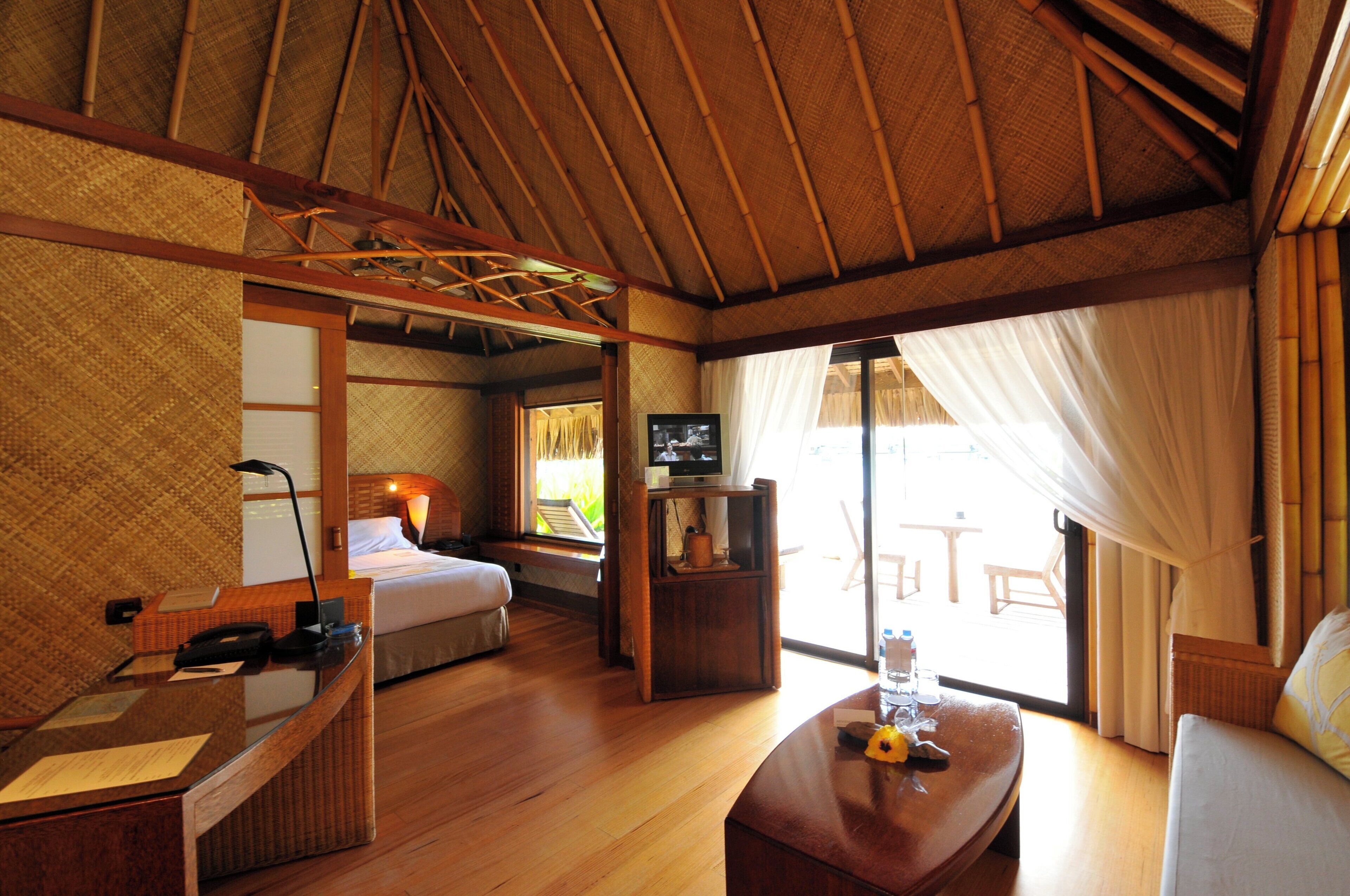 Una habitación con cama, escritorio, televisor y vista al exterior.