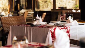 A dining area with tables set for two, featuring white napkins, cutlery, and glassware.