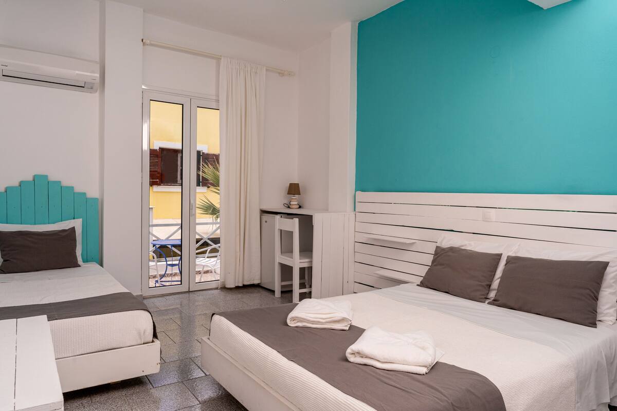 A hotel room with a bed, a desk, and a view of the outside.