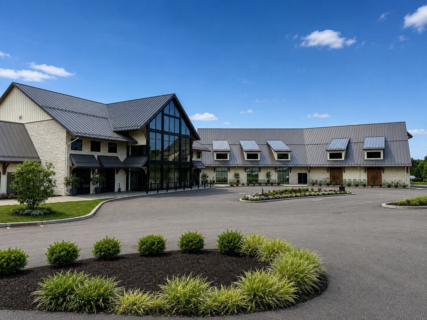 A modern building with a large glass facade, multiple entry points, and a landscaped driveway.