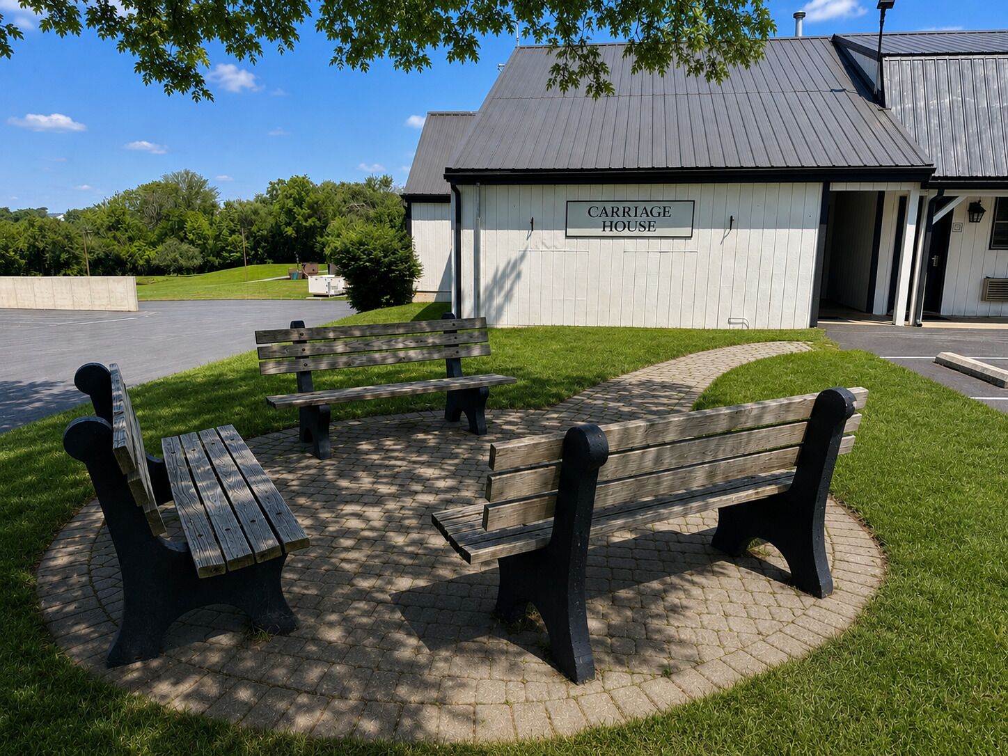 A park area with a Carriage House labeled building, benches, and a paved walkway.