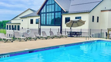 Una piscina al aire libre, sombrillas, sillones reclinables de piscina