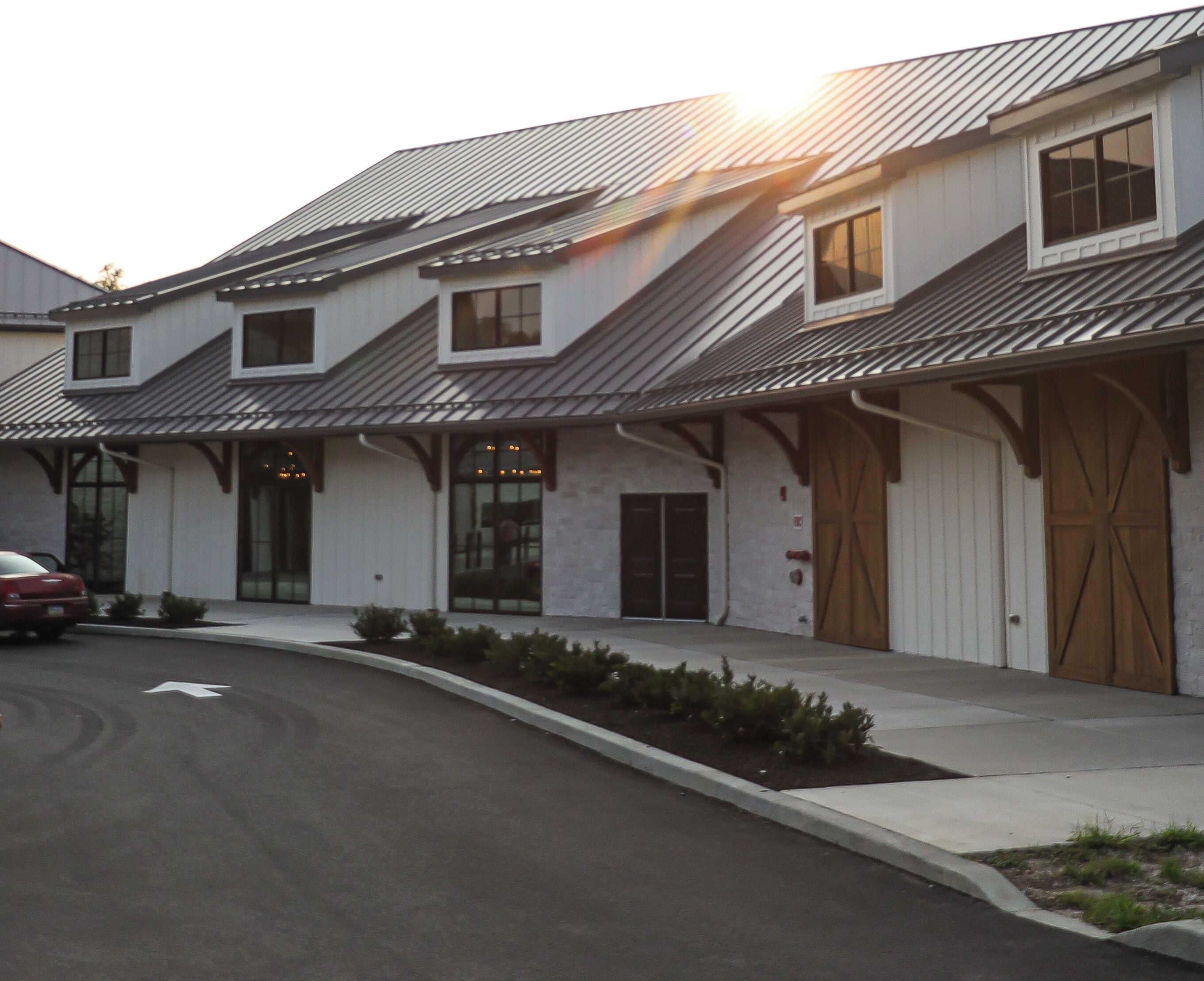 A modern two-story building with a sloped roof, large windows, and a garage door.