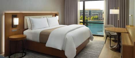 A hotel room with a large bed, a desk, and a view of a swimming pool.