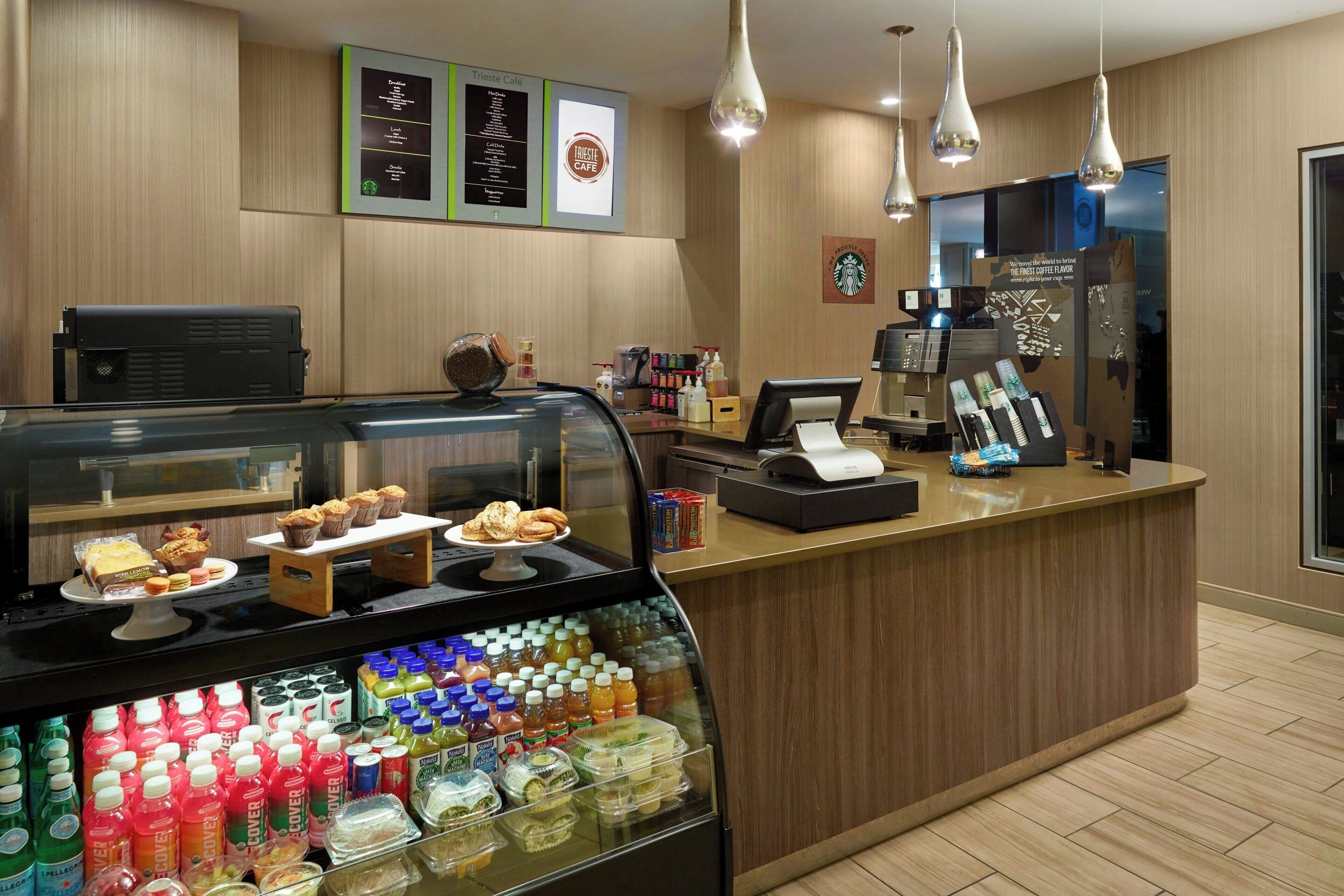 A coffee shop counter with a display case of pastries and a selection of beverages.