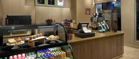 A coffee shop counter with a display case of pastries and a selection of beverages.