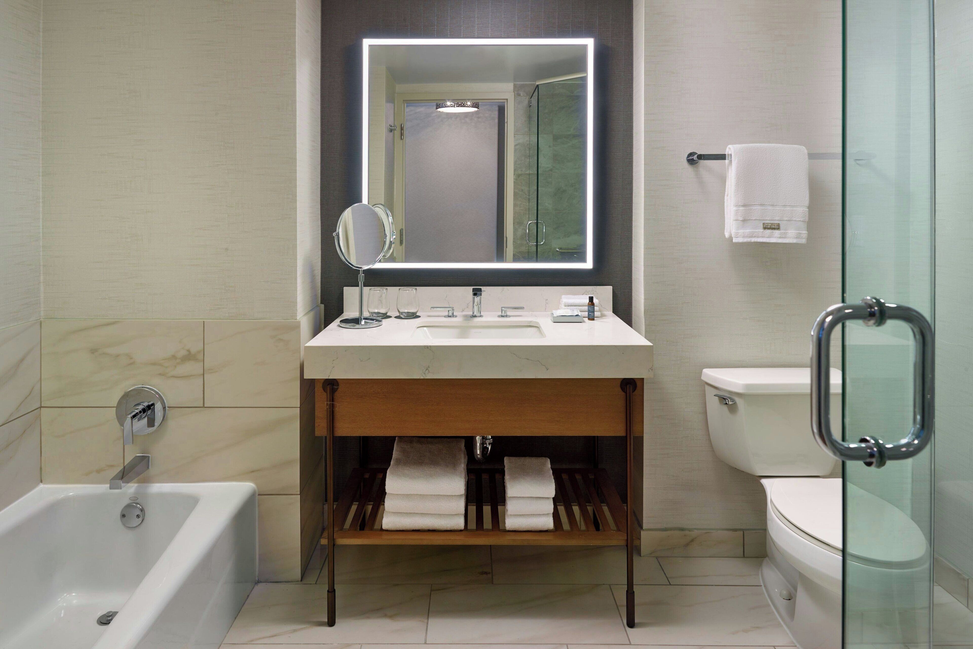 A modern bathroom with a white sink, mirror, and bathtub.