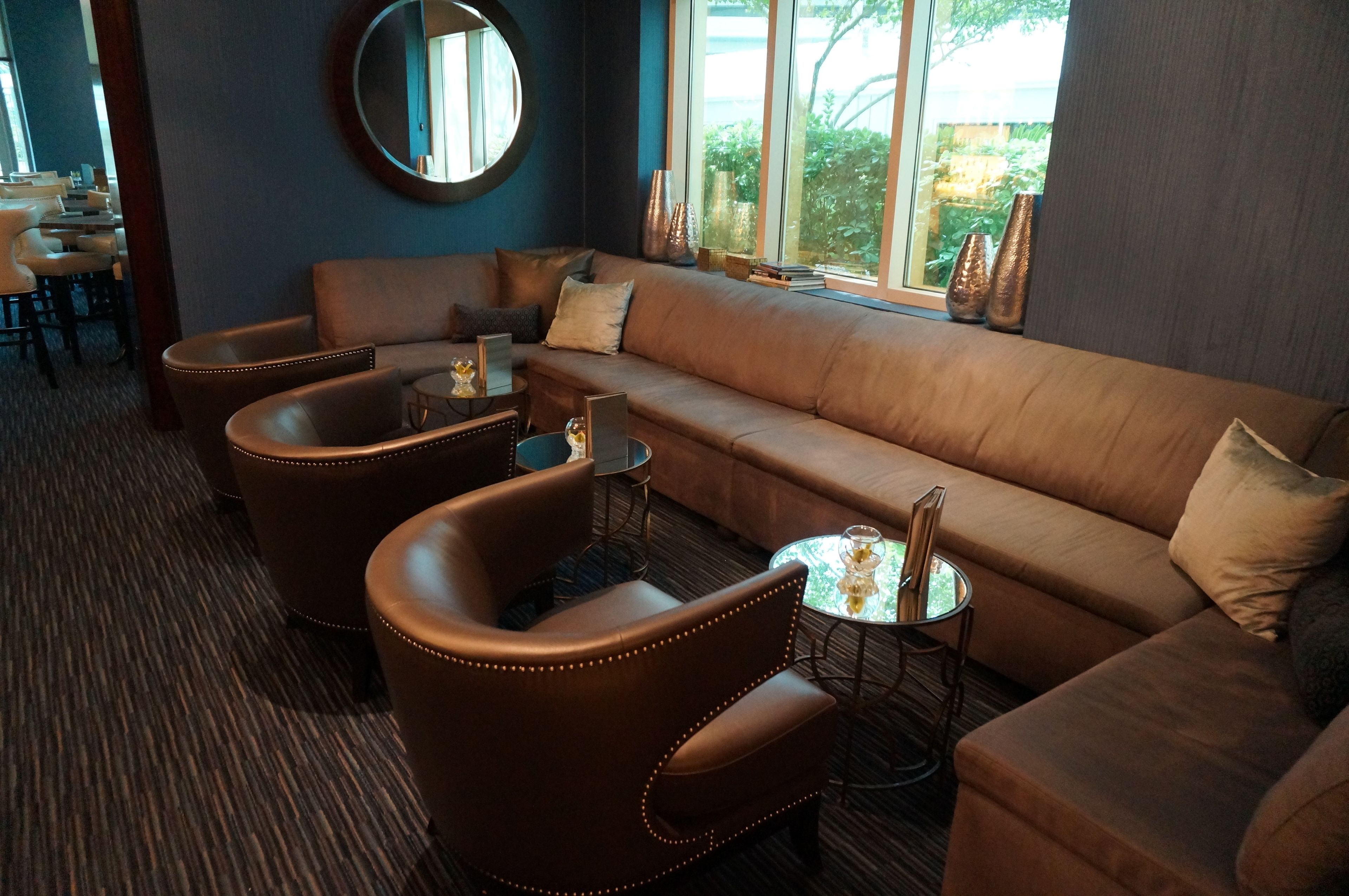 Un espace de détente moderne avec un canapé en cuir marron, deux fauteuils et une petite table ronde.
