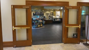 A Starbucks Coffee entrance with a frosted glass door, a tiled floor, and a visible interior with a counter and display cases.