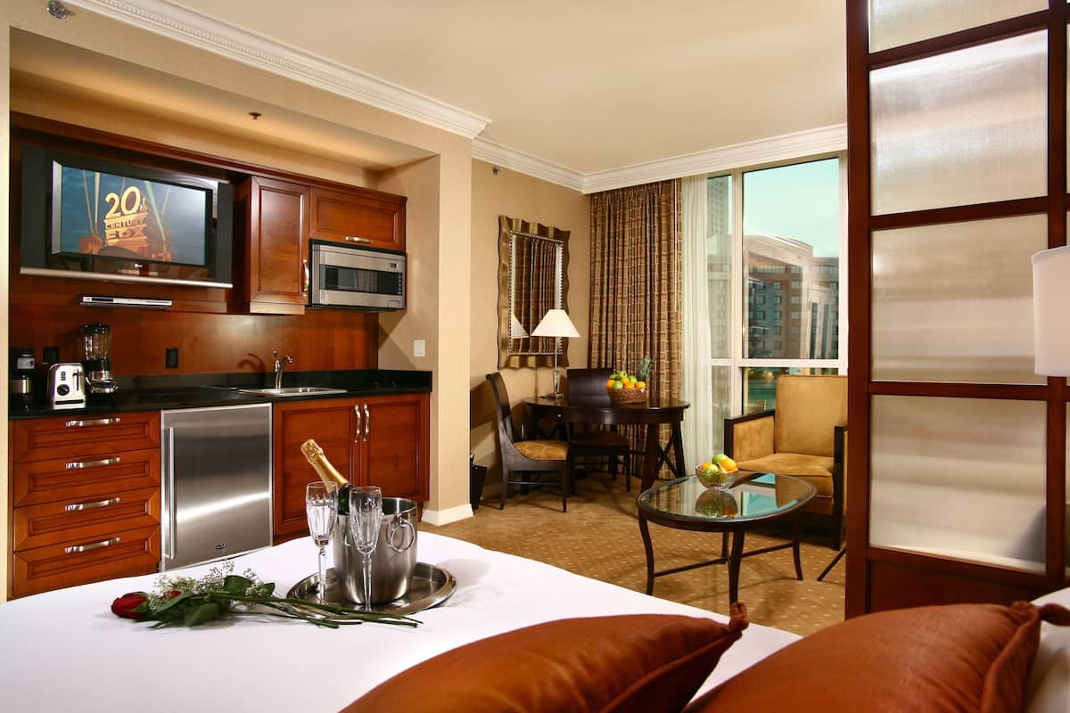 Una habitación de hotel con kitchenette, comedor y cama.