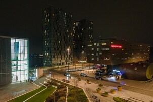Un hotel moderno con fachada de vidrio, un llamativo letrero rojo y un diseño arquitectónico único.