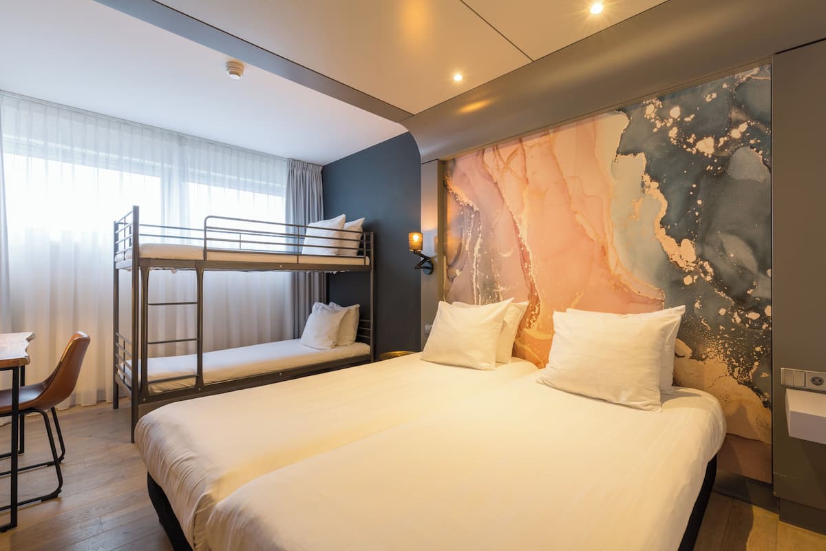 A hotel room with two beds, a desk, and a chair.