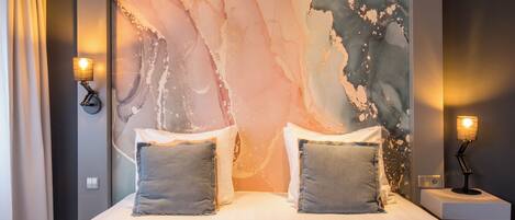 A modern hotel room with a large bed, two bedside lamps, and a marble wall mural.