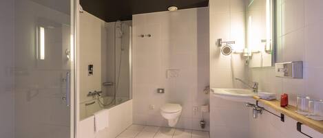 A modern bathroom with a glass-enclosed shower, a toilet, a sink, and a mirror.