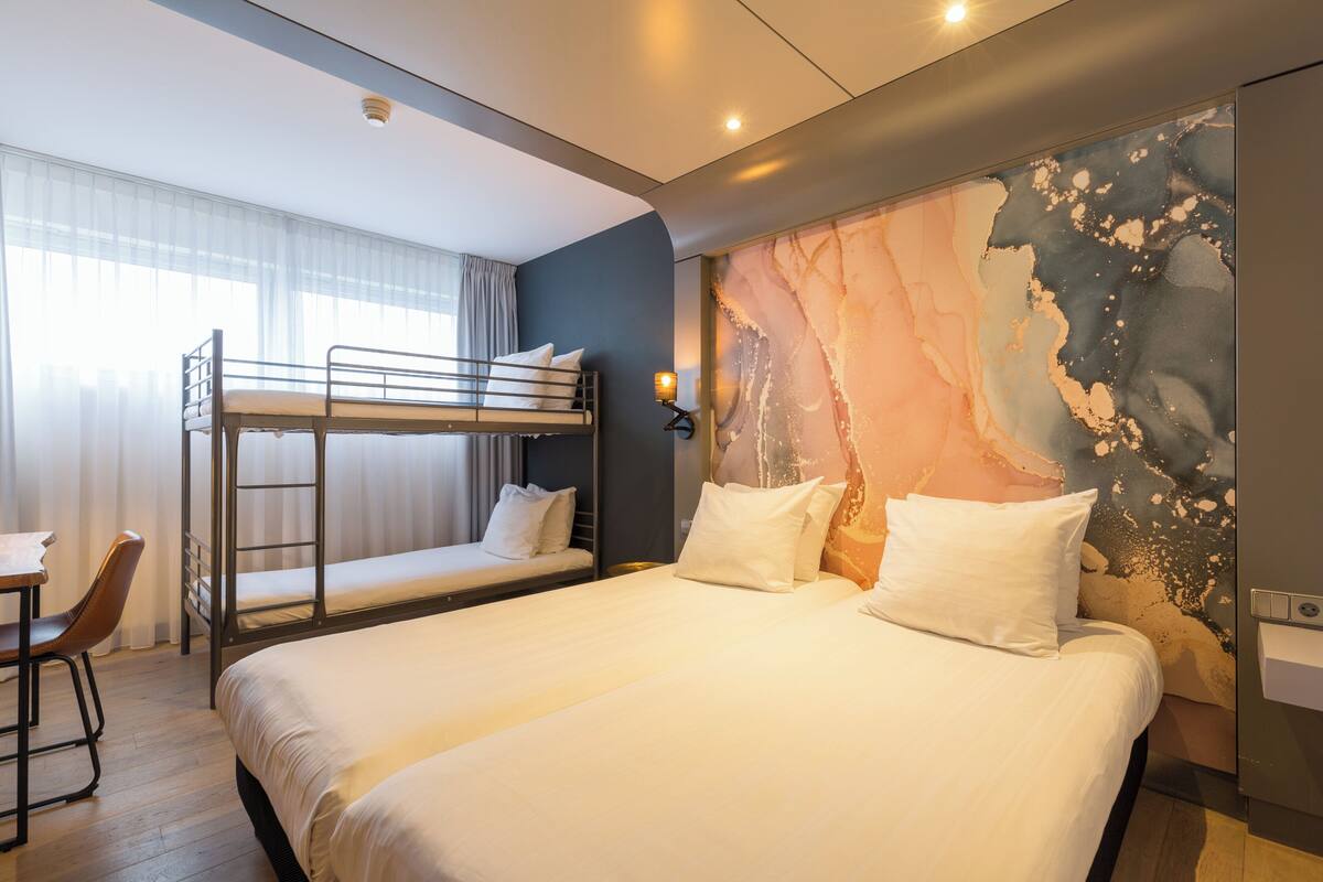 A hotel room with two beds, a desk, and a chair.