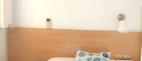 A hotel room with a bed, a nightstand, a painting on the wall, a lamp, and a window.