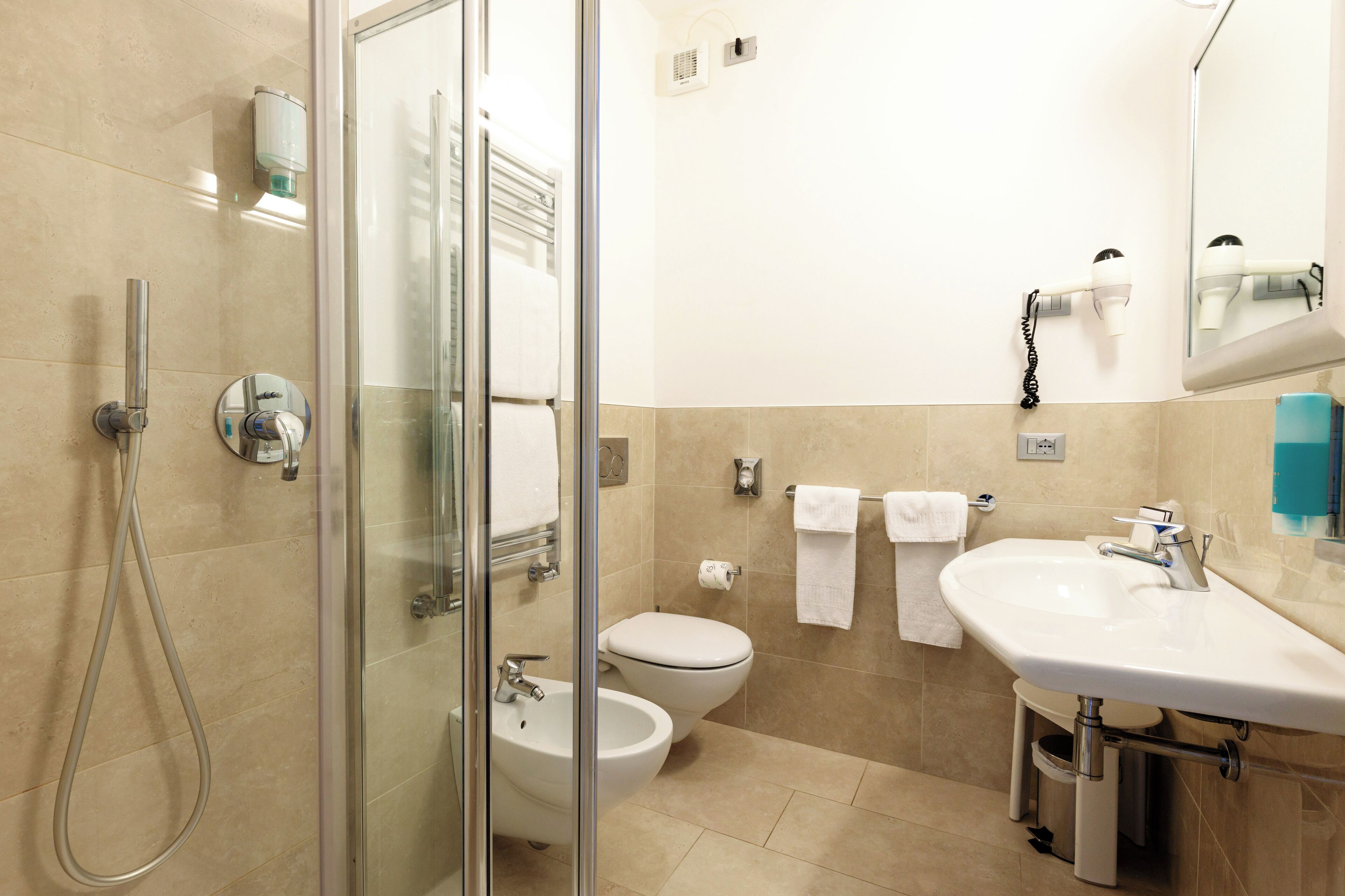 Un baño moderno con cabina de ducha de vidrio, inodoro, bidé y lavabo con espejo.