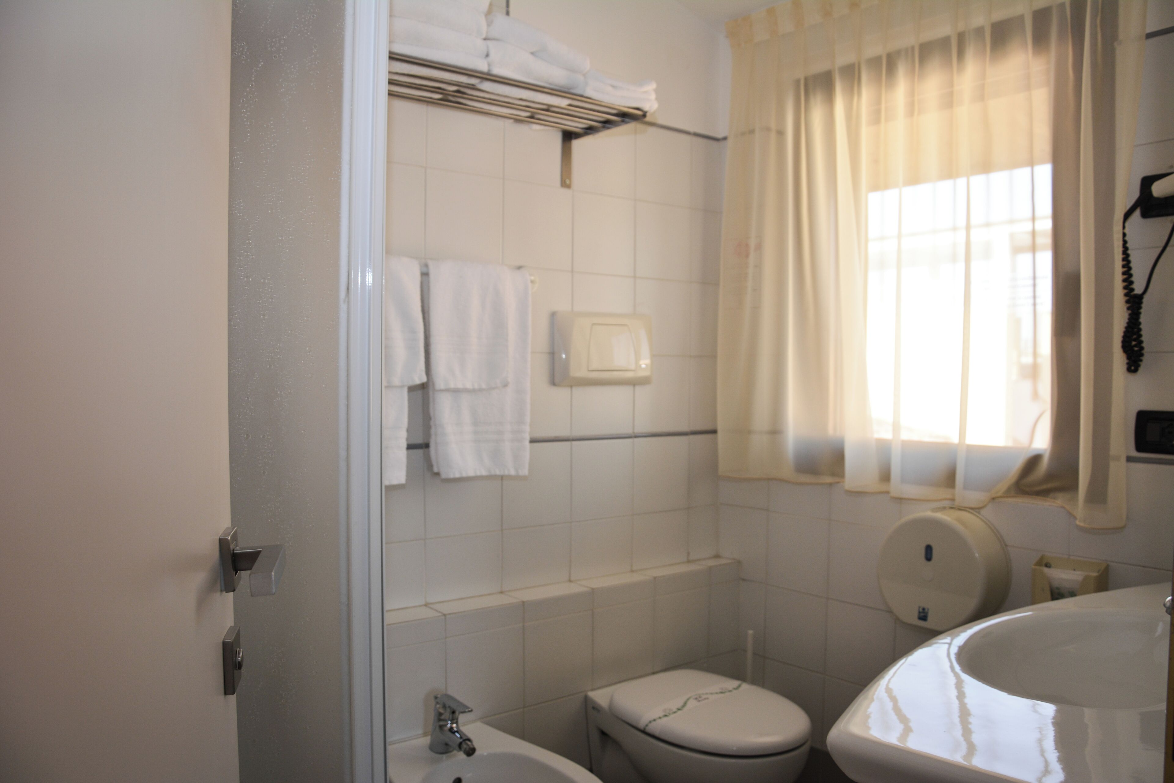 Et badeværelse med toilet, vask og håndklædetørrer.