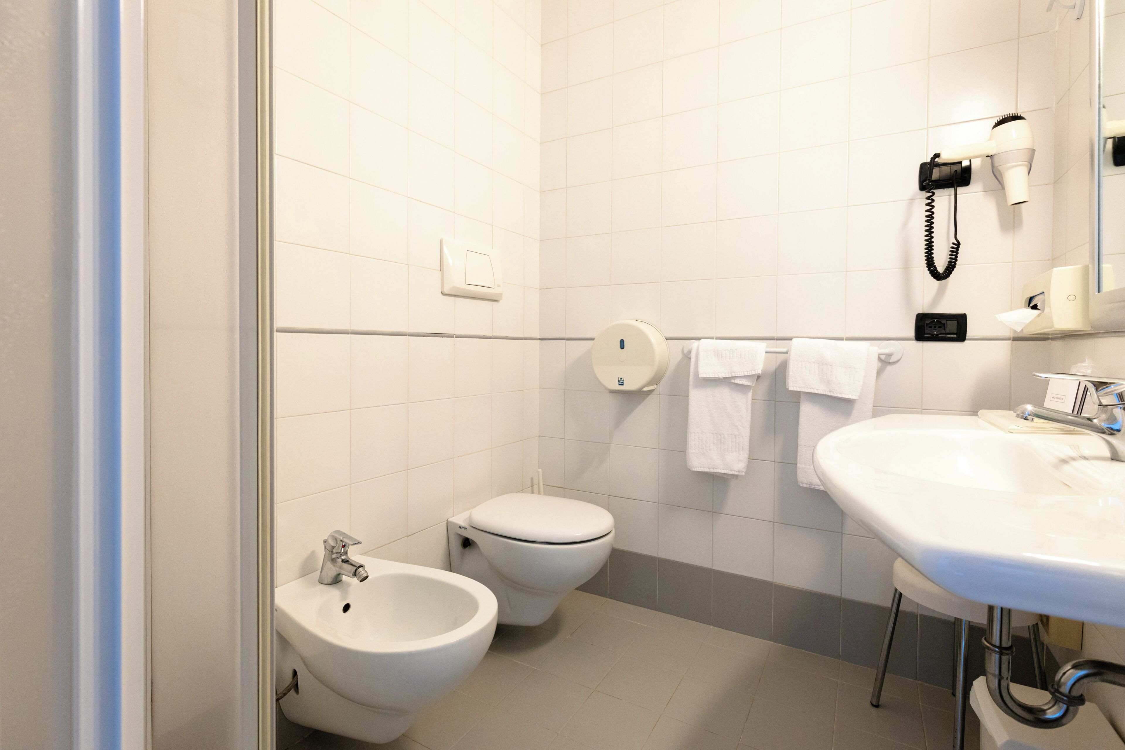 A bathroom with a bidet, toilet, and sink.