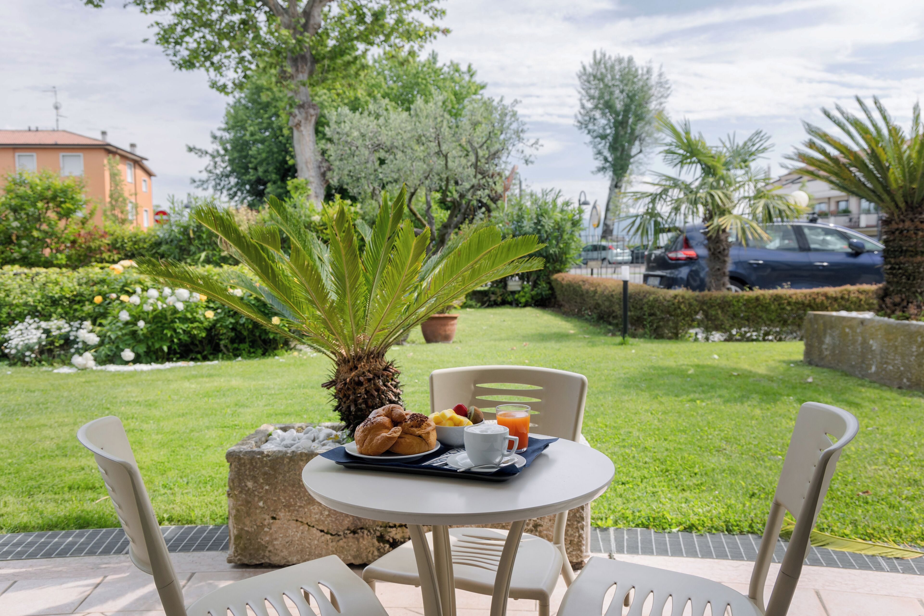 An outdoor dining area with a table set for breakfast, including croissants, fruit, and juice.