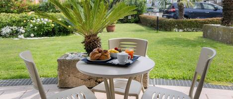 An outdoor dining area with a table set for breakfast, including croissants, fruit, and juice.