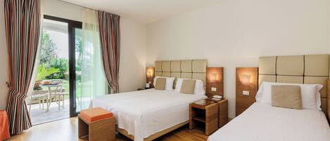 Quarto de hotel com duas camas, uma mesinha e vista para o exterior.