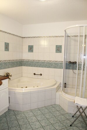 A bathroom with a large bathtub, a shower enclosure, and a vanity with a mirror. - Seltenbacher Hof (Tuttlingen)