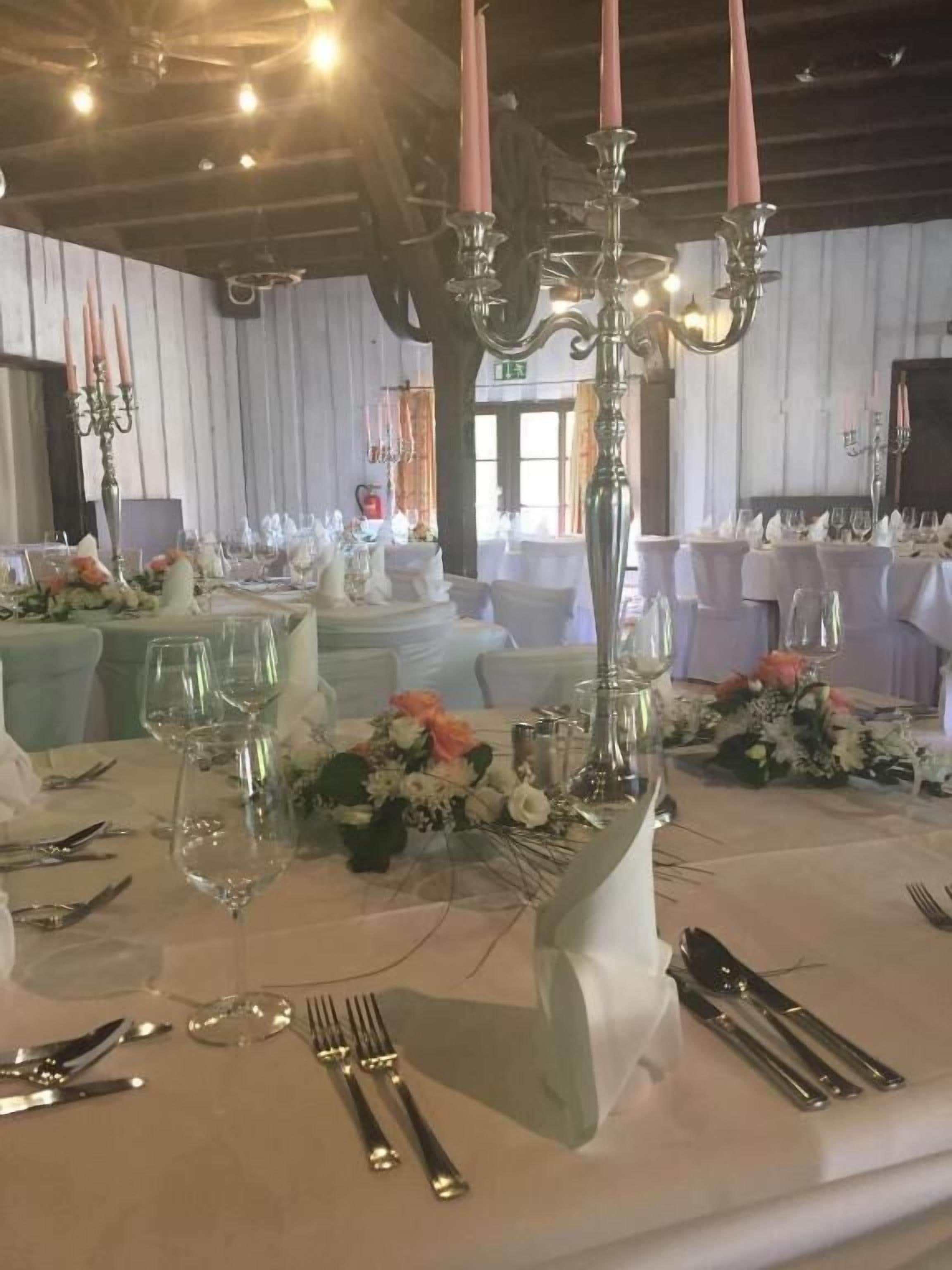 A banquet hall with tables set for a formal event, featuring floral centerpieces and elegant tableware.