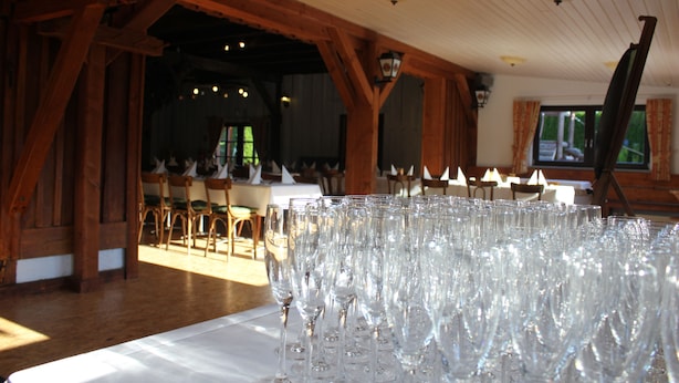 A room with wooden beams, a table with multiple wine glasses, and a television in the background. - Seltenbacher Hof (Tuttlingen)