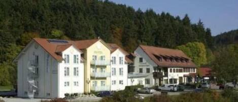 A hotel with multiple buildings, including a large white building with a red roof and a smaller building with a yellow facade.