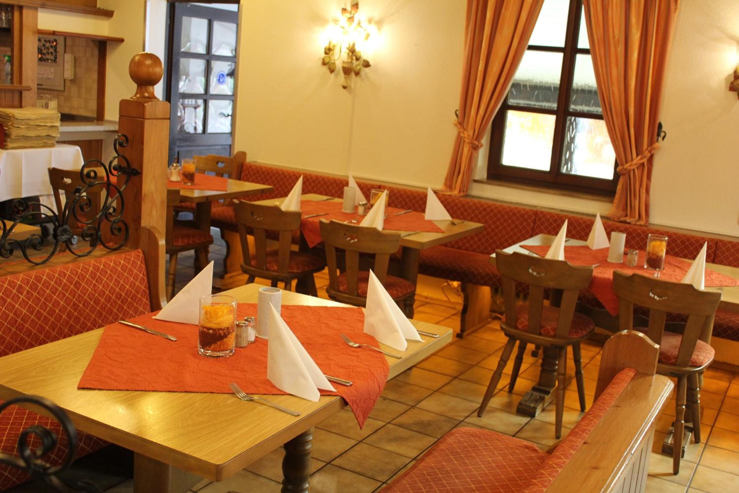 Un restaurant avec des tables et des bancs en bois, chaque table étant équipée d’une serviette et d’un verre.