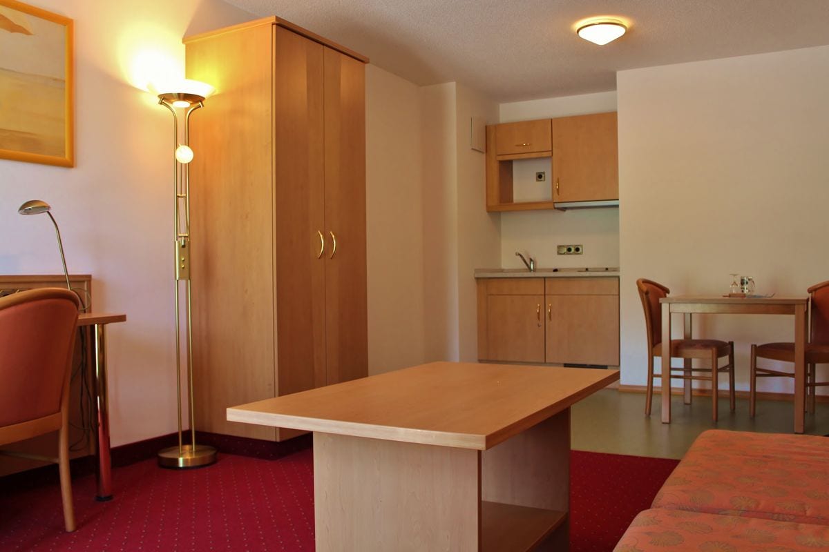 A compact room with a kitchenette, a dining area, and a bed.
