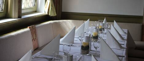 A dining table set for a meal with white tablecloths, glassware, and floral centerpieces.